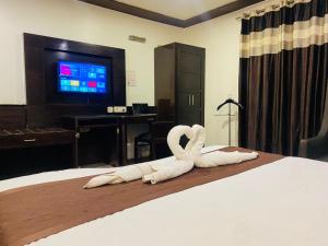 a hotel room with a bed with towel swans on it at Qotel Hotel Pitampura Couple Friendly in New Delhi