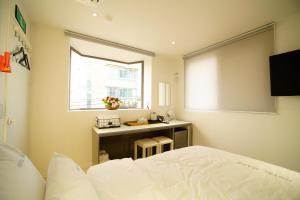 a bedroom with a bed and a desk and a window at Hotel MARE in Busan