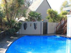 a swimming pool in a yard with a fence and trees at Wild Tree Lodge in Benoni