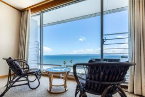 a room with chairs and a large window with a view of the ocean at Spa and Resort Hotel Solage Oita Hiji Beppuwan in Beppu