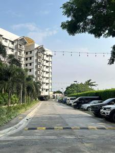 DMCI Alea Residences 2BR في مانيلا: موقف للسيارات مع وقوف السيارات أمام المبنى
