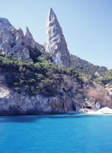 uma montanha na costa de uma praia com água azul em Splendida villa in riva al mare em Orosei