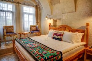 a bedroom with a large bed in a room with windows at Petra Inn Cappadocia in Uçhisar