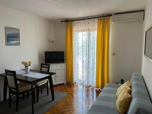 a living room with a blue couch and a table and yellow curtains at Apartments Dujmović in Rovinj