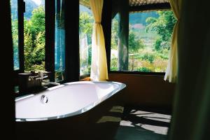 a bath tub in a room with a large window at Moc Chau Retreat in Mộc Châu