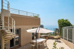 een patio met een witte parasol en een tafel bij Les Terrasses de Monaco in Roquebrune-Cap-Martin