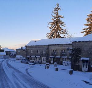 eine schneebedeckte Straße mit einem Gebäude und einem Baum in der Unterkunft Casa Aldeia da Lapa in Sernancelhe