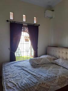 a bedroom with a large bed with a window at Omah Medina in Klaten