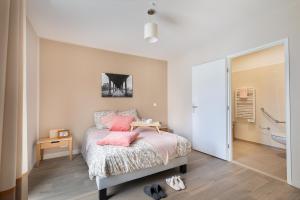 a bedroom with a bed with pink pillows and a bathroom at Zenao Appart'hôtels Le Raincy in Le Raincy