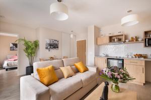 a living room with a couch and a kitchen at Zenao Appart'hôtels Le Raincy in Le Raincy