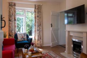 a living room with a fireplace and a red chair at The Lookout in Fritham