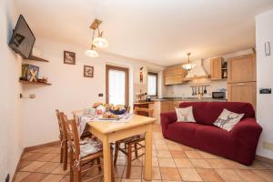 a living room with a table and a red couch at Chalet La Garde in Valtournenche