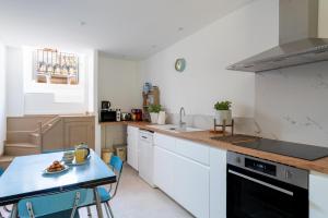 a kitchen with white cabinets and a table with a plate of food at Appart Casa Zio Vaison la Romaine in Vaison-la-Romaine