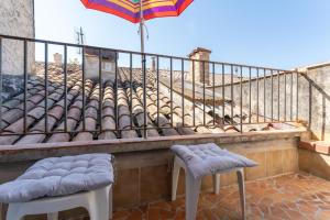 a balcony with two stools and an umbrella at Appart Casa Zio Vaison la Romaine in Vaison-la-Romaine