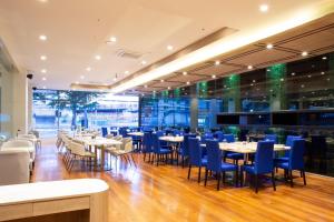 a dining room with tables and blue chairs at Le Srivaree Suvarnabhumi Airport Hotel in Samutprakarn