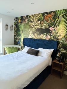 a bedroom with a blue bed with a tropical wallpaper at Stunning Riverside View Apartment, near Canary Wharf & O2 in London