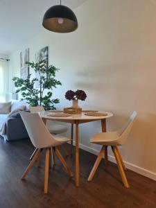 a dining room table with two chairs and a vase with flowers at VENICE VILLA Apartment, self check-in 24h, free parking in Poznań