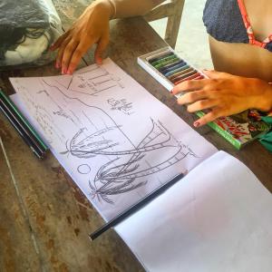 a person is drawing on a table with a pencil at Ganesh Gate in Pottuvil