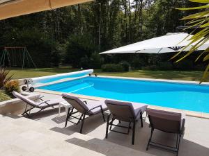 een zwembad met stoelen, een tafel en een parasol bij Logement aux portes de chambord in Mont-près-Chambord