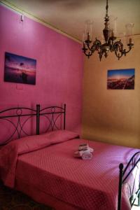 a pink bedroom with a bed with a red bedspread at L' Arco Antico in Caccamo