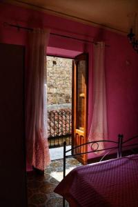 a bedroom with pink walls and a bed and a window at L' Arco Antico in Caccamo