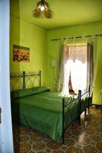 a green bedroom with a bed and a window at L' Arco Antico in Caccamo