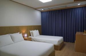 ソギポにあるSoldongsan Stayのベッド2台と青いカーテンが備わるホテルルームです。