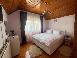 um quarto com uma grande cama branca e uma janela em Vila Tequila Sinaia em Sinaia