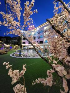 Heaven Hill Hotel & Hot Spring في Cham Ta Lao: مبنى فيه نافورة وشجرة فيها ورد ابيض