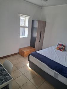 1 dormitorio con cama, mesa y ventana en Partridge Place, en Kempton Park