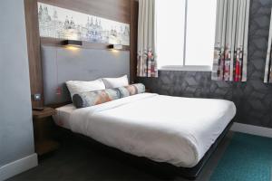 a bedroom with a large bed with white sheets and pillows at Aloft Liverpool in Liverpool