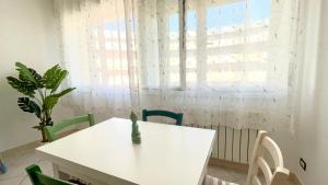 uma mesa branca e cadeiras num quarto com uma janela em Imperiale Apartment em Tirrenia