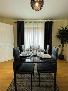 comedor con mesa negra y sillas en Majestic House - Milton Keynes Serviced Accommodation, en Milton Keynes