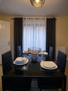 een eetkamer met een tafel en stoelen met wijnglazen bij Majestic House - Milton Keynes Serviced Accommodation in Milton Keynes