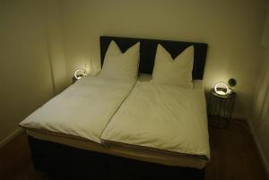 Una cama con sábanas blancas y almohadas. en Ferienwohnung Felsterrasse, en Wasserliesch