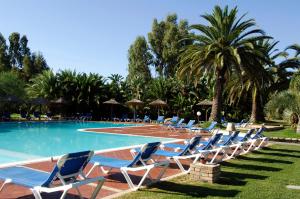 a group of lounge chairs next to a swimming pool at Classical Residence Baia delle Palme Premium num1210 in Santa Margherita di Pula