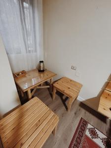 um quarto com mesas e bancos de madeira e uma janela em At Pikotiko's - Korca City Rooms for Rent em Korçë