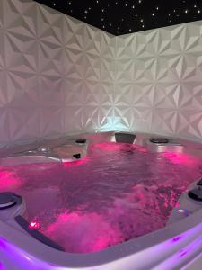 - un bain à remous avec éclairage rose dans la chambre dans l'établissement LES SECRETS ROOMS - BONNEVILLE - LOVE ROOM 130m2 - SPA PRIVATIF, à Bonneville