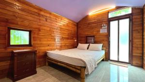 a bedroom with a bed in a wooden wall at Phu Nam House - Resort in Phú Quốc