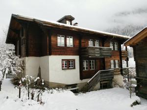 uma grande casa de madeira com neve no chão em Im Mättelti em Niederwald