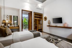 - une chambre avec 2 lits et une télévision murale dans l'établissement Sarang Cocoon Villa Ubud by BaliSuperHost, à Ubud