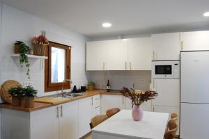 a kitchen with white cabinets and a table with a vase on it at Casa El Cuarto con preciosas vistas en Candelaria in Candelaria