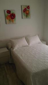 1 cama en un dormitorio con 2 pinturas en la pared en Antonio Fernández Playa, en Conil de la Frontera