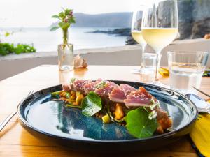 a plate of food on a table with wine glasses at King Fisher Village in Tarrafal