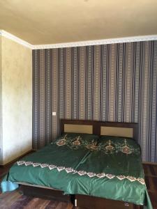 um quarto com uma cama verde e uma parede listrada em Hotel Today , Խաղաղության լողափ em Shorzha