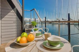 a table with a bowl of fruit on a balcony at Hausboot - Svanehus in Heiligenhafen