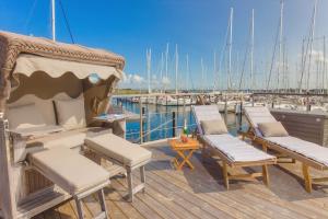 a deck with chairs and tables and boats in a marina at Hausboot - Svanehus in Heiligenhafen