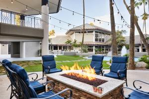 eine Terrasse mit einer Feuerstelle und Stühlen sowie ein Haus in der Unterkunft Delta Hotels by Marriott Phoenix Mesa in Mesa