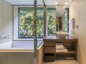 a bathroom with a tub and a sink and a window at Solaria Nishitetsu Hotel Kyoto Premier in Kyoto