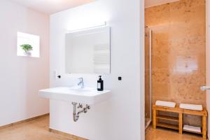 a white bathroom with a sink and a shower at stycoz: Modernes Loft in der historischen Altstadt Memmingen in Memmingen